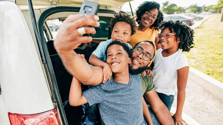Family taking selfie by car