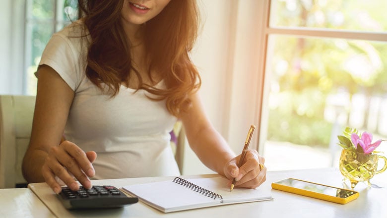 woman calculating and writing in notebook