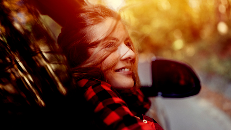 Young woman in plaid enjoying a fall drive