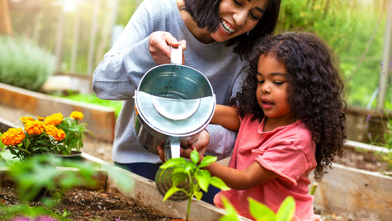 Mom and daughter watering flowers together