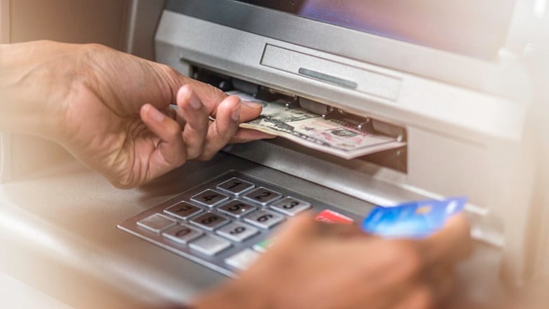 closeup view of hands removing money from ATM