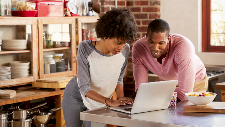 young couple in kitchen looking at computer